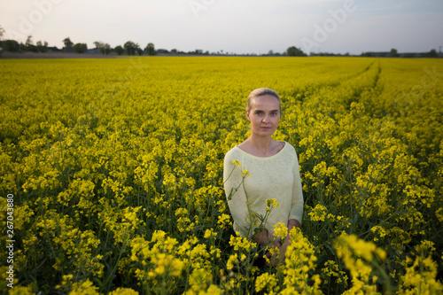 Happy woman on blooming rapeseed field in springin yellow blouse. photo