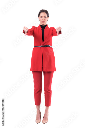 Displeased angry business woman in red suit showing disapproval thumbs down hand sign. Full body isolated on white background.