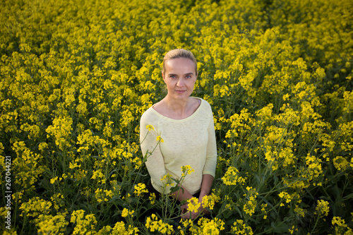 Happy woman on blooming rapeseed field in springin yellow blouse. photo