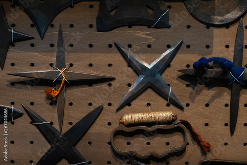 Closeup of collection of authentic and original rusty vintage Japanese Shuriken Ninja Throwing Stars and Knuckle Duster attached to wall photo