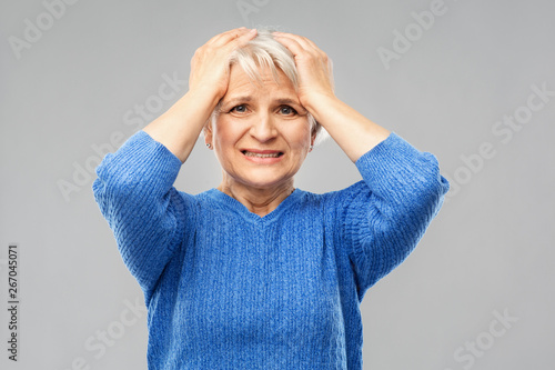 stress, emotions and old people concept - portrait of stressed senior woman in blue sweater holding to her head over grey background