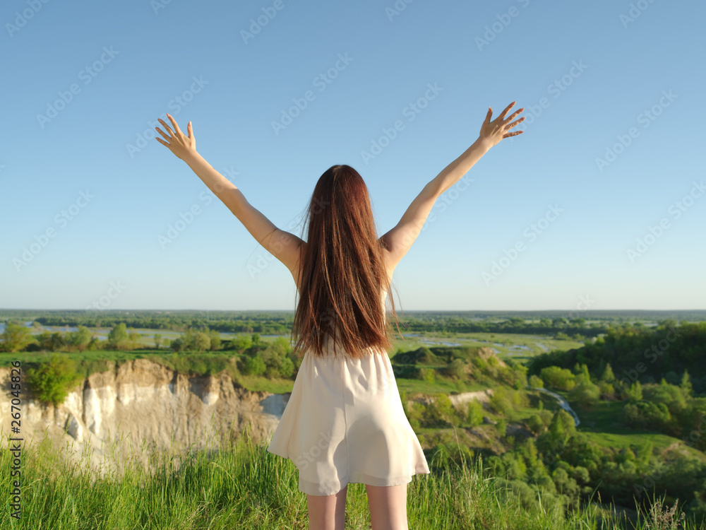Young woman stands with her arms raised up to the sky. Young woman stands with her arms raised up to the sky.