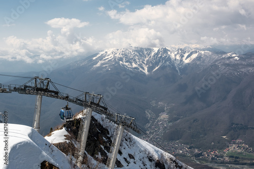 Cable car on top of Aibga mountain, in the village of Krasnaya Polyana, Sochi. Blue clear sky with clouds. Tourist season in the mountains. photo