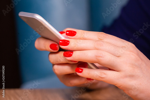 close-up  female hands with red manicure use a smartphone on a white background. Limited depth of field