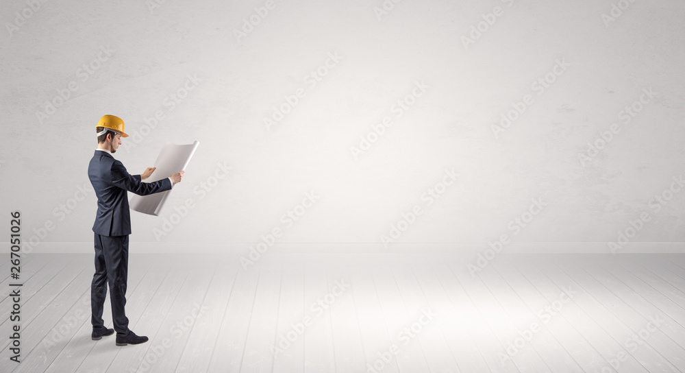Young architect with construction helmet standing in an empty space and holding a plan
Young architect with construction helmet standing in an empty space and holding a plan