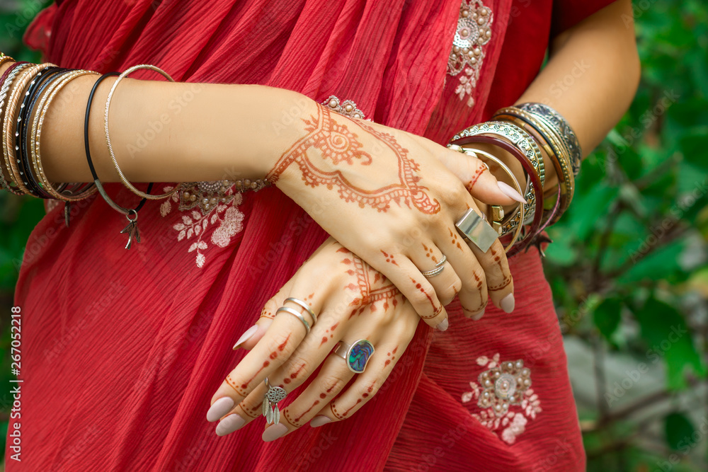 Beautiful woman wear traditional Muslim Arabic Indian wedding red pink sari dress hands with henna tattoo mehndi pattern jewelry and bracelets Happy holiday summer culture festival celebration concept