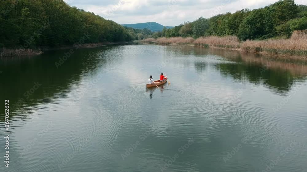 Couple paddling in a wooden boat. Young man and woman paddling canoe on lake Couple paddling in a wooden boat. Young man and woman paddling canoe on lake