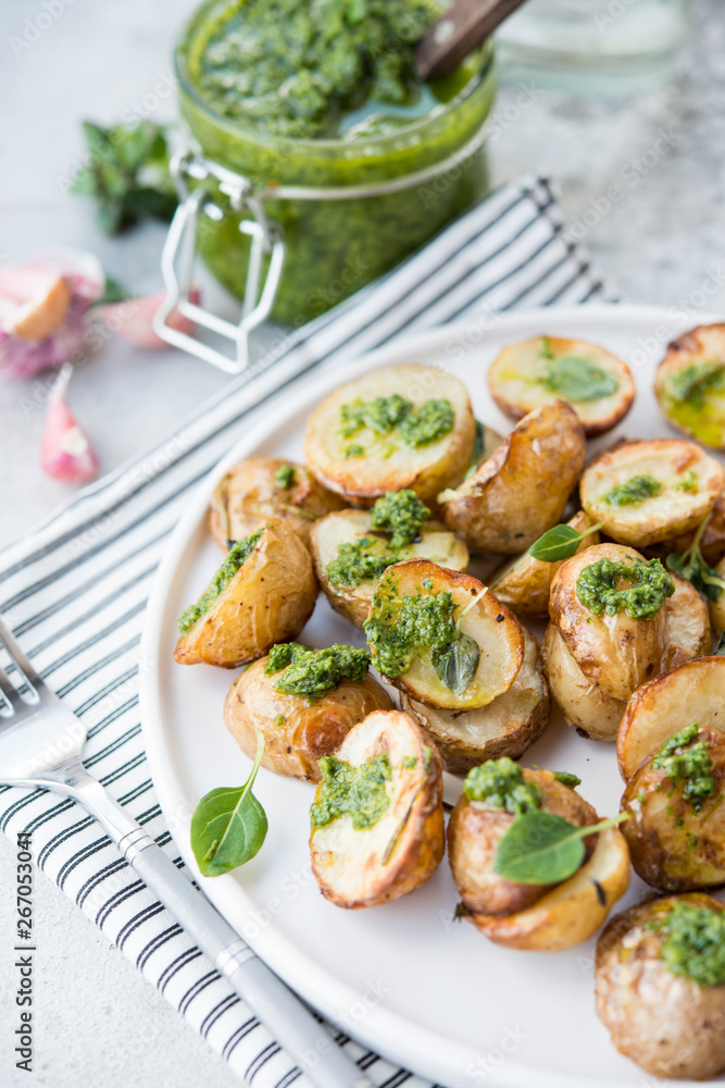 Baked potatoes in rustic style with green pesto sauce Baked potatoes in rustic style with green pesto sauce