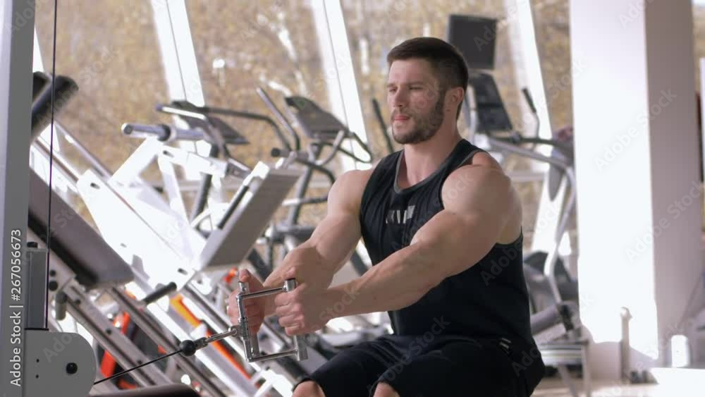 professional athlete guy doing muscle building workout on traction simulator while working on body at fitness club professional athlete guy doing muscle building workout on traction simulator while working on body at fitness club