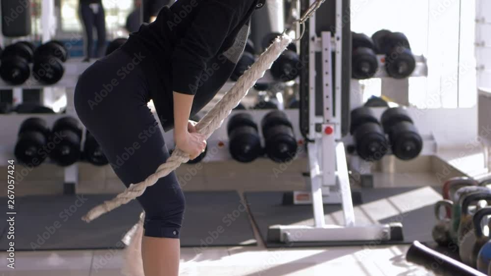 sport female doing muscle building workout on traction simulator while training on body at fitness club sport female doing muscle building workout on traction simulator while training on body at fitness club