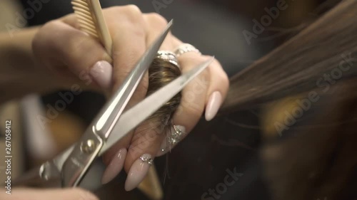 hairdresser with perfect beige almond nails and golden ring makes brown hair thinning professionally close view