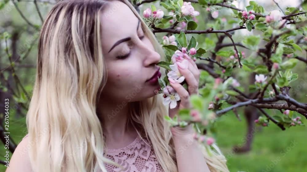 Closeup portrait of a woman in spring among flowering trees. A woman enjoys the smell of flowers. Closeup portrait of a woman in spring among flowering trees. A woman enjoys the smell of flowers.