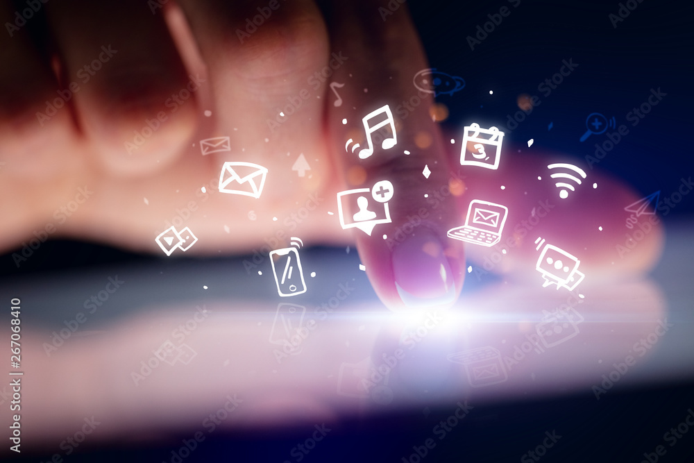 Finger touching tablet with hologram application icons and dark background
