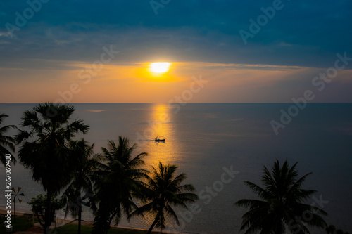 Silhouette fishing boat on skin sea water color gold at sunrise time.