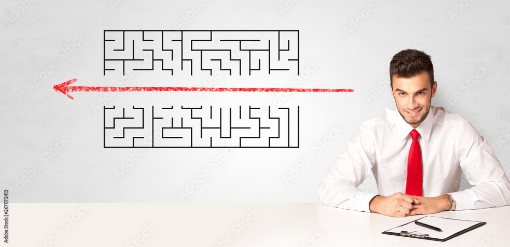 Businessman presenting a maze on a wall
Businessman presenting a maze on a wall