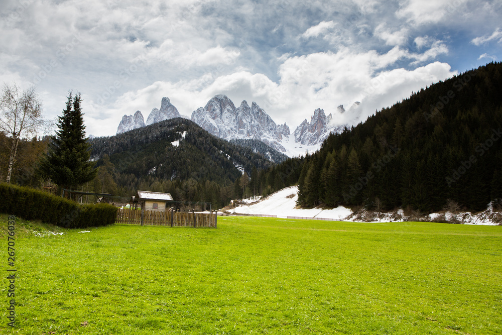 Beautiful mountain scenery in the Alps with fresh green meadows in bloom on a beautiful sunny day in springtime. Dolomiti montains in Italy. Landscape in spring in Europe.