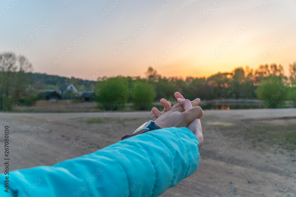 Romantic couple holding hands and watching the beautiful sunset. Man and woman hold hands, arms stretched forward