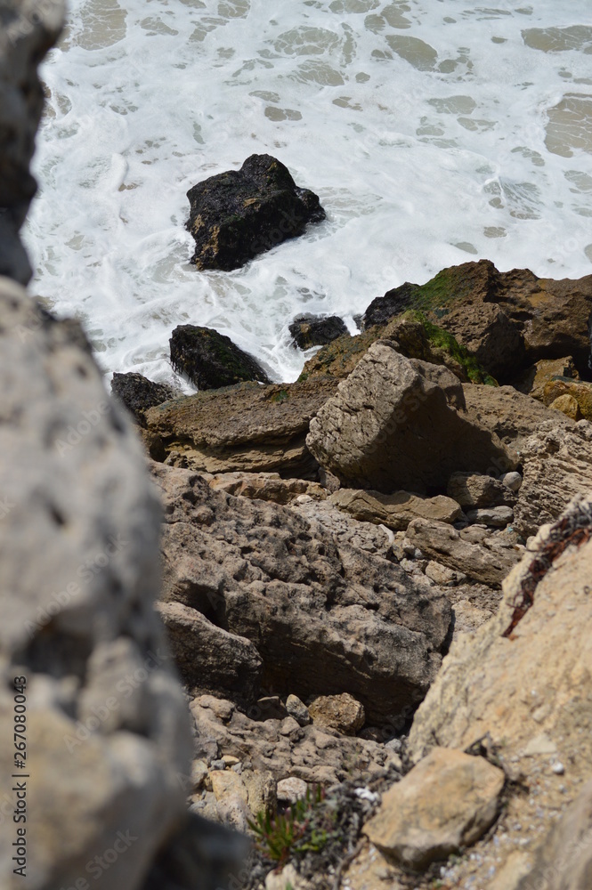 Fototapeta premium Rocky Cliff On The Beautiful Beach Of Cresmina In Cascais. Photograph of Street, Nature, architecture, history, Geology. April 15, 2014. Cascais, Lisbon, Portugal.