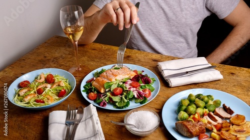 Man with fork and tasty delicious dinner, salmon salad