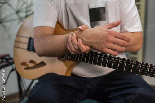 Canvas Print Musician having wrist pain while playing electric guitar in home music studio