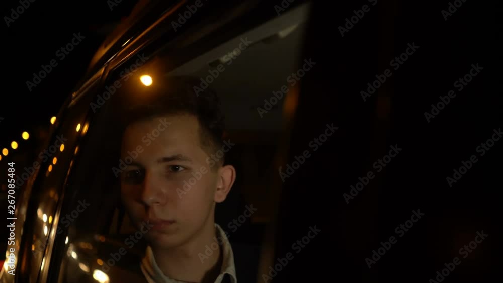 Portrait of young handsome teenager traveling in a taxi car with a driver in night city. 4k footage Portrait of young handsome teenager traveling in a taxi car with a driver in night city. 4k footage