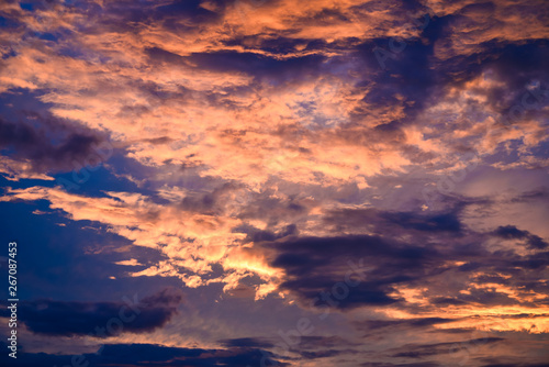 Summer colorful sunset with sunlight, pink, blue clouds. Beautiful summertime landscape for poster, print, surface, cover, interior decor. Sun rays breaking through the clouds. Bright light, dusk