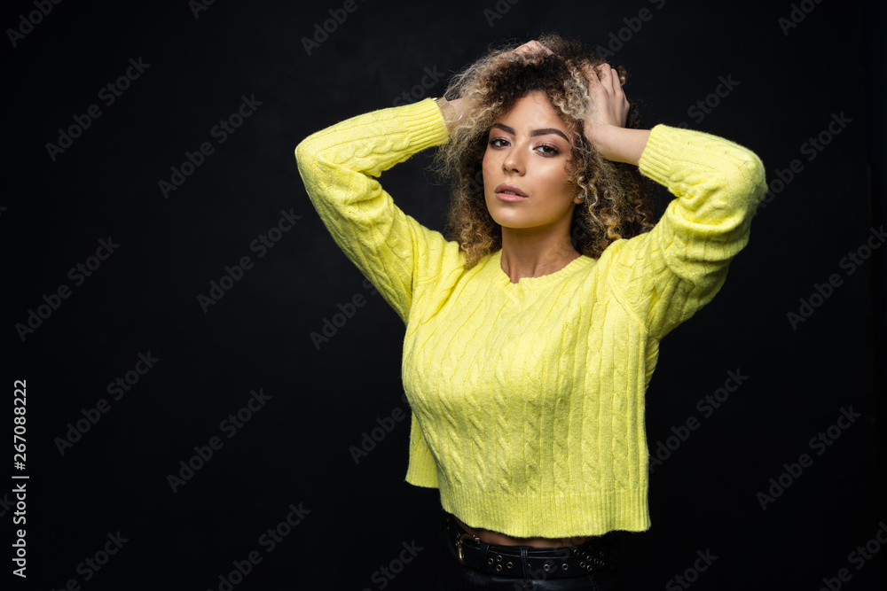 Portrait of a beautiful black female fashion model with curly hair over black background. Portrait of a beautiful black female fashion model with curly hair over black background.