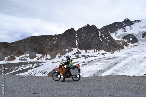 Motorcyclist on the background of snowy mountains in the Alps.