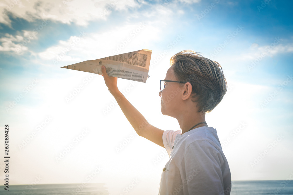 Happy child playing with paper airplane at sunset, dreaming about ...