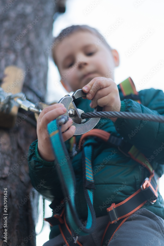 Obraz premium Little boy in a rope park. Active physical recreation of the child in the fresh air in the park. Training for children.