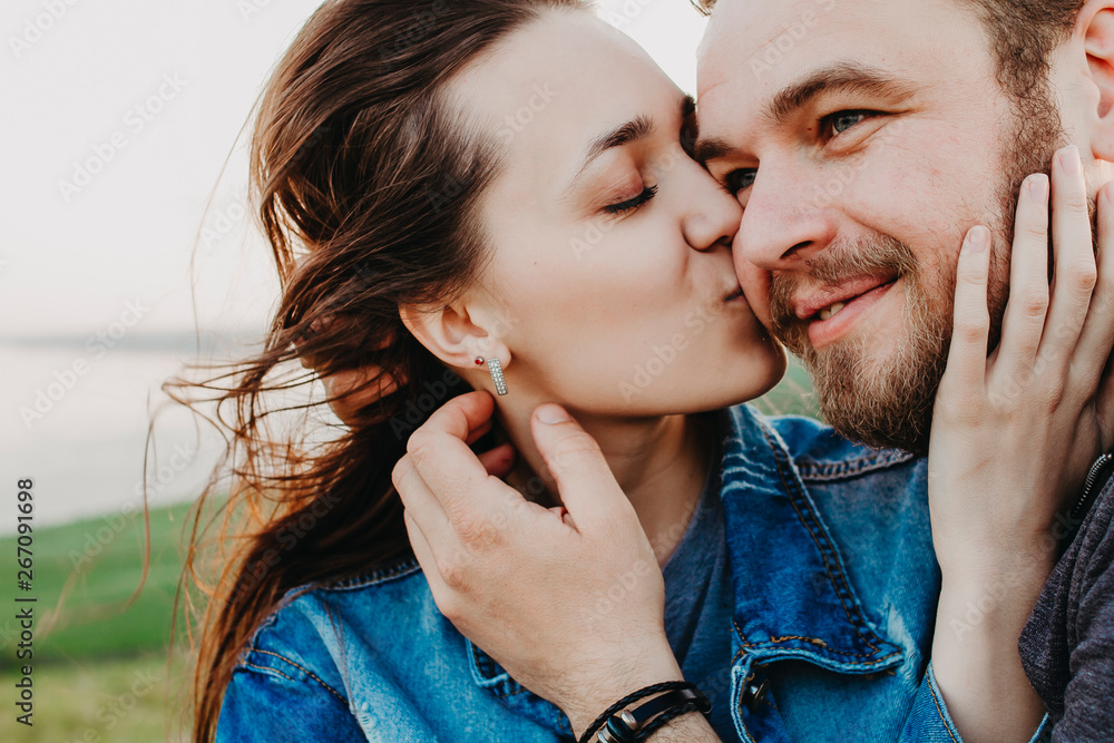 A beautiful woman in love kisses her man with her eyes closed, a man smiles A beautiful woman in love kisses her man with her eyes closed, a man smiles