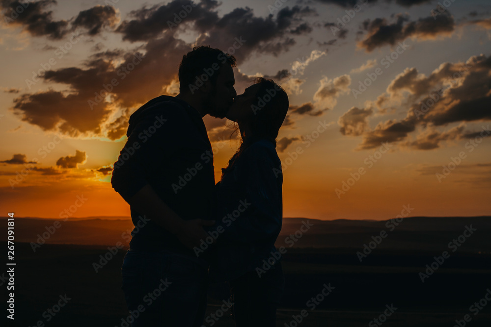Silhouette of man and woman kissing at sunset