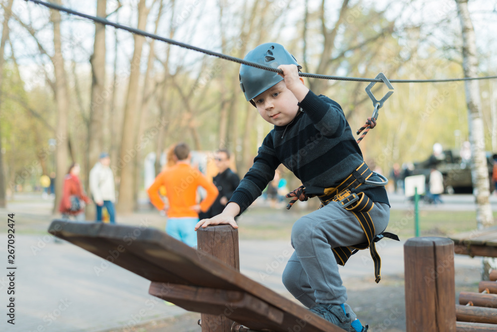 A little boy is passing an obstacle course. Active physical recreation of the child in the fresh air in the park. Training for children. A little boy is passing an obstacle course. Active physical recreation of the child in the fresh air in the park. Training for children.