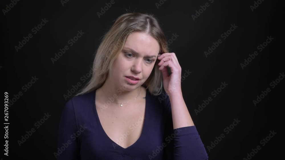 Middle-aged blonde businesswoman in blue blouse with scoop neckline suffering from headache on black background. Middle-aged blonde businesswoman in blue blouse with scoop neckline suffering from headache on black background.