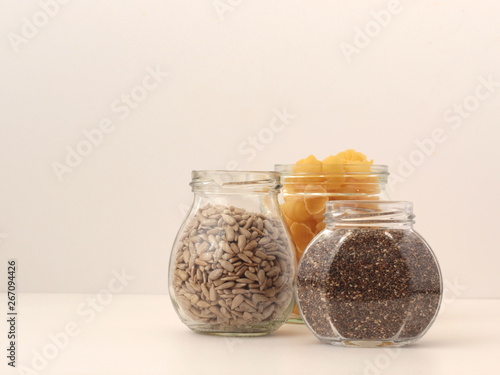 Three recycled jars used to store dried goods, namely pasta, chia seeds and sunflower seeds. Concept of recycling and zero-waste lifestyle. photo