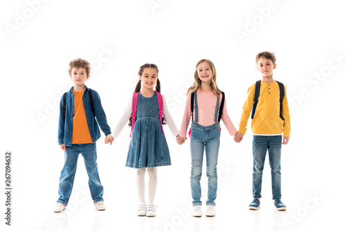 full length view of schoolchildren with backpacks holding hands isolated on white