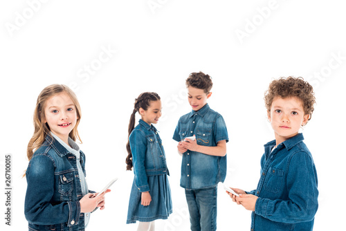 four kids in denim clothes using smartphones isolated on white