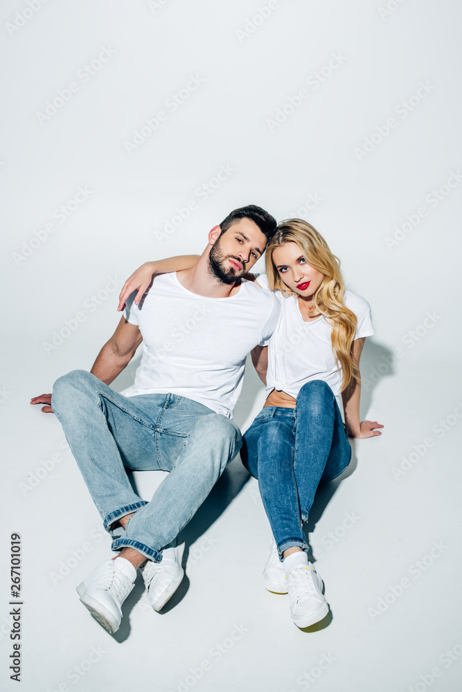 attractive girl and handsome man looking at camera while sitting on white attractive girl and handsome man looking at camera while sitting on white