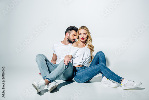 handsome bearded man sitting and looking at attractive blonde girl on white