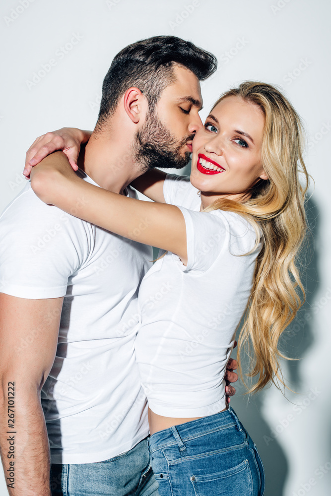 handsome bearded man kissing cheek of happy blonde girl on white handsome bearded man kissing cheek of happy blonde girl on white