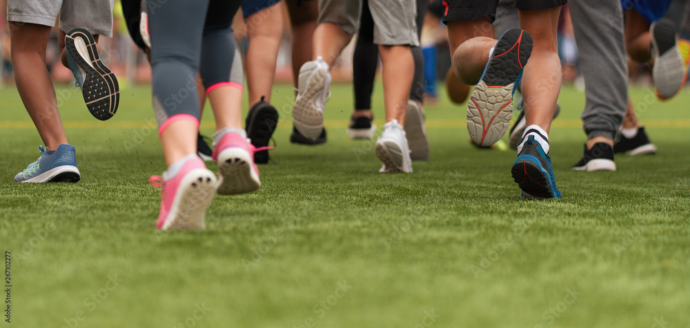 Running children, young athletes run in a kids run race, running on grass detail on legs, running in the light of morning Running children, young athletes run in a kids run race, running on grass detail on legs, running in the light of morning
