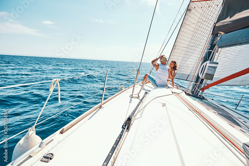 Happy woman with man relaxing on sailboat deck.