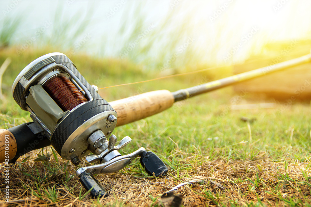 Fishing activities. rod with baitcasting reel on the grass wait for the  fish to stick or eat to the hook on natural background and copy space.  Stock Photo
