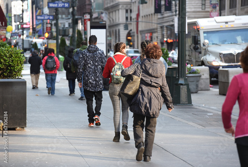 A group of people walk along the sidewalk in Manhattan