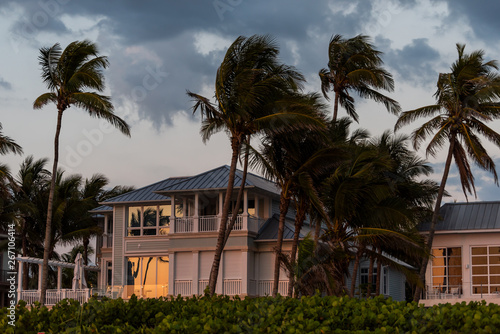 Coast house beachfront waterfront vacation home, house during evening sunset with nobody in Florida, gulf of mexico, stormy weather and wind on palm trees