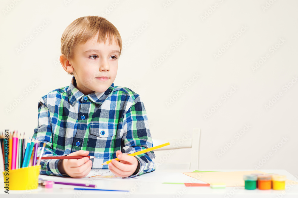 Cute little boy draws with pencils in daycare center. Creative kid class. Children, hobby, childhood and happy people concept. Home schooling concept. Copy space Cute little boy draws with pencils in daycare center. Creative kid class. Children, hobby, childhood and happy people concept. Home schooling concept. Copy space