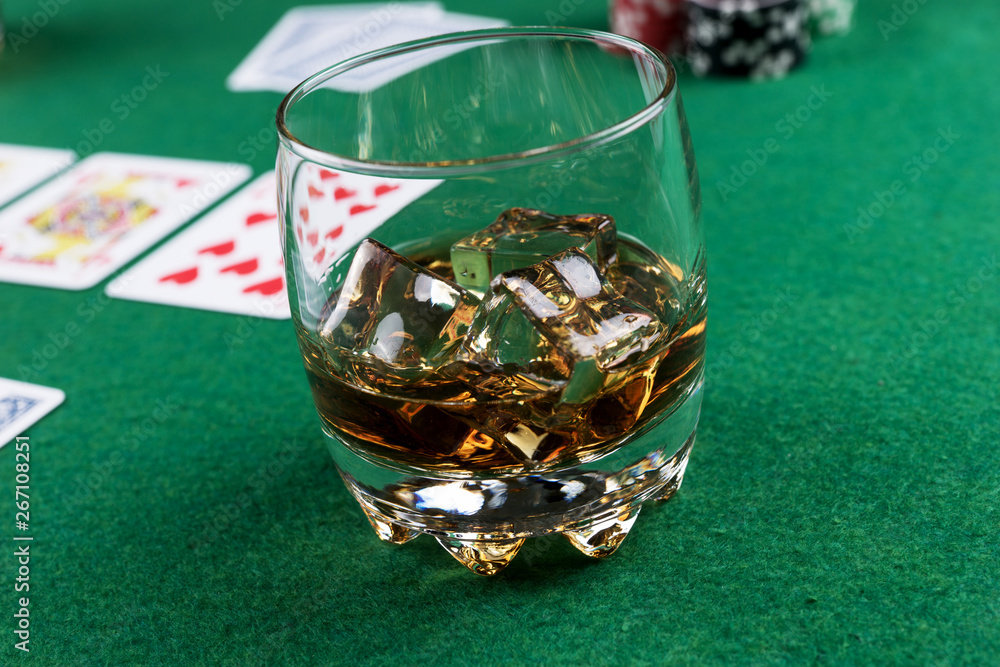Glass of Scotch on Ice on the poker table with cards and chips Glass of Scotch on Ice on the poker table with cards and chips