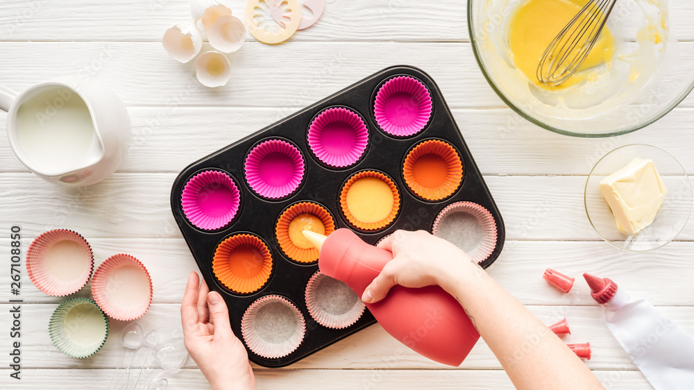 cropped view of woman pouring liquid dough in cupcake pan on table cropped view of woman pouring liquid dough in cupcake pan on table