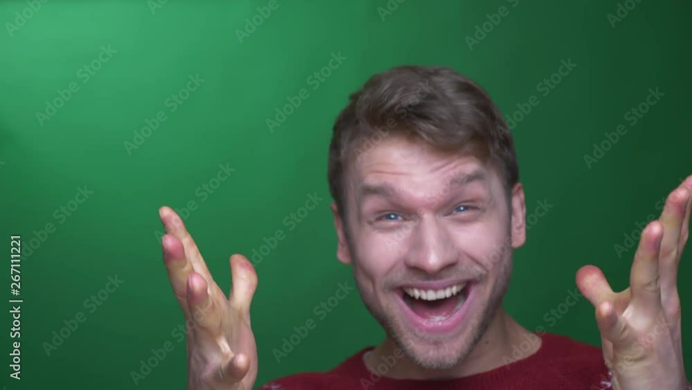 Young brunette businessman in sweater shows extreme happiness and gesticulating joyfully on green background. Young brunette businessman in sweater shows extreme happiness and gesticulating joyfully on green background.