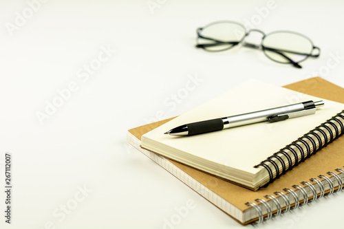 pen on diary book and glasses on white desk background.